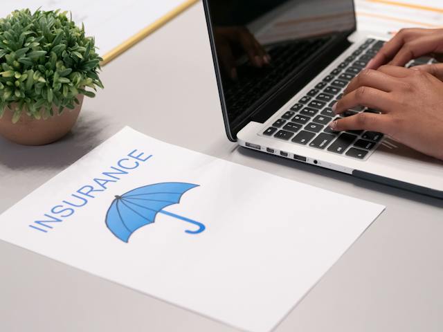 person at computer next to insurance paper