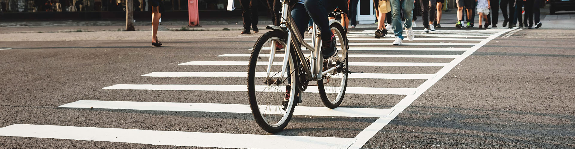 A bike lane and street crosswalk with people riding bicycles, crossing in an urban city setting. Kane County Bicycle Accident Lawyer concept image